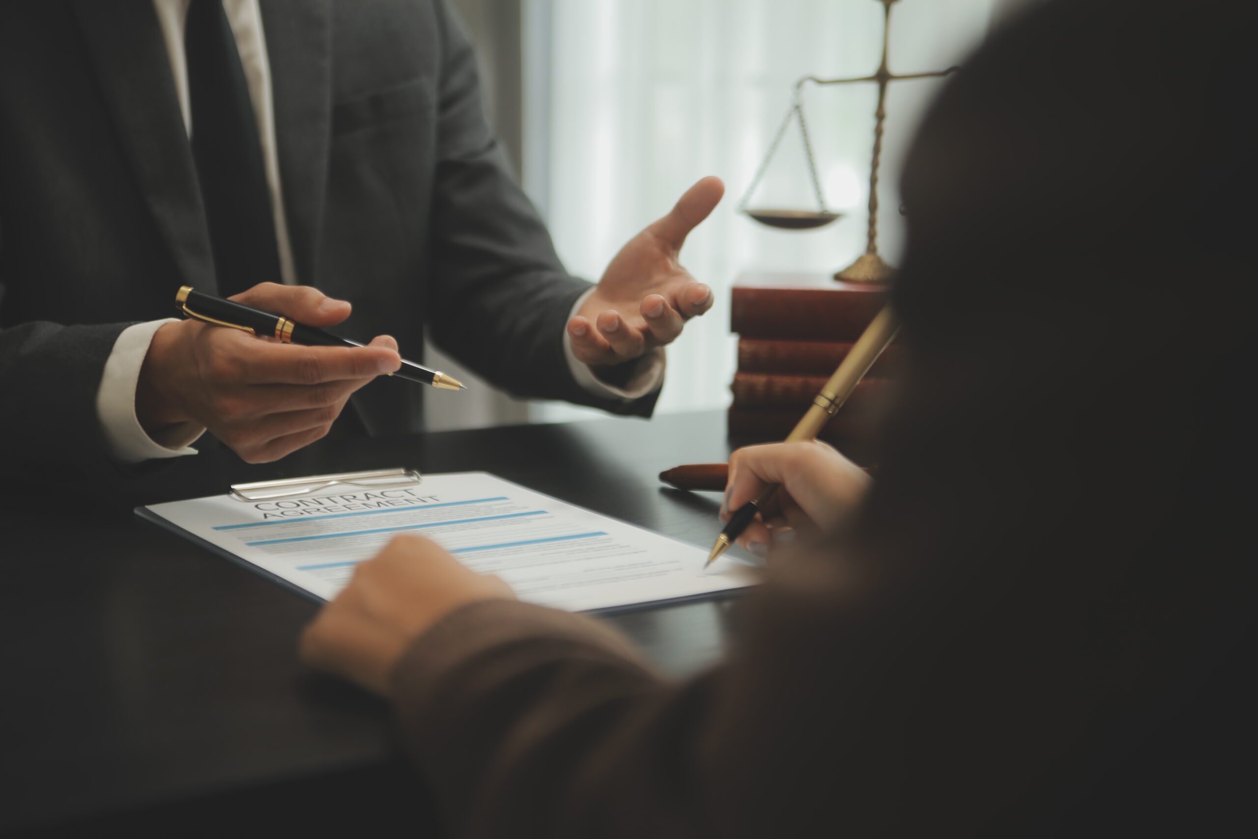 Business and lawyers discussing contract papers with brass scale on desk in office. Law, legal services, advice, justice and law concept picture with film grain effect